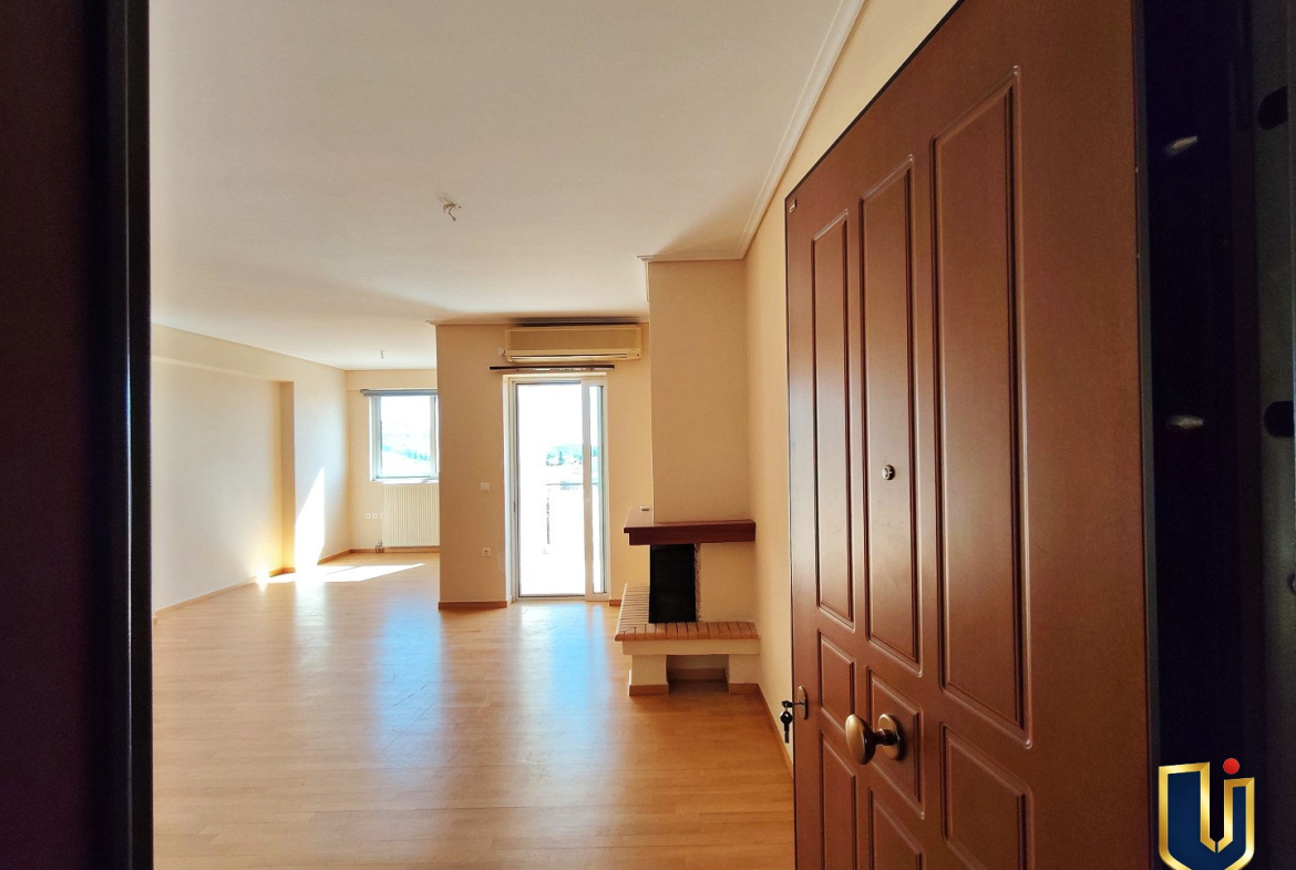 Entrance to a Paiania apartment with parquet flooring, a living room fireplace and balcony doors