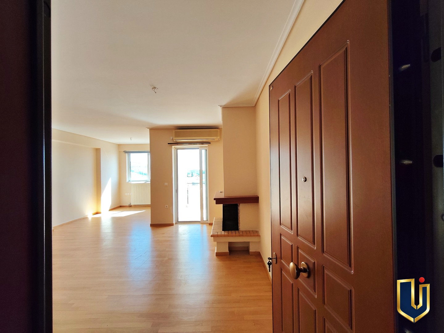 Entrance to a Paiania apartment with parquet flooring, a living room fireplace and balcony doors