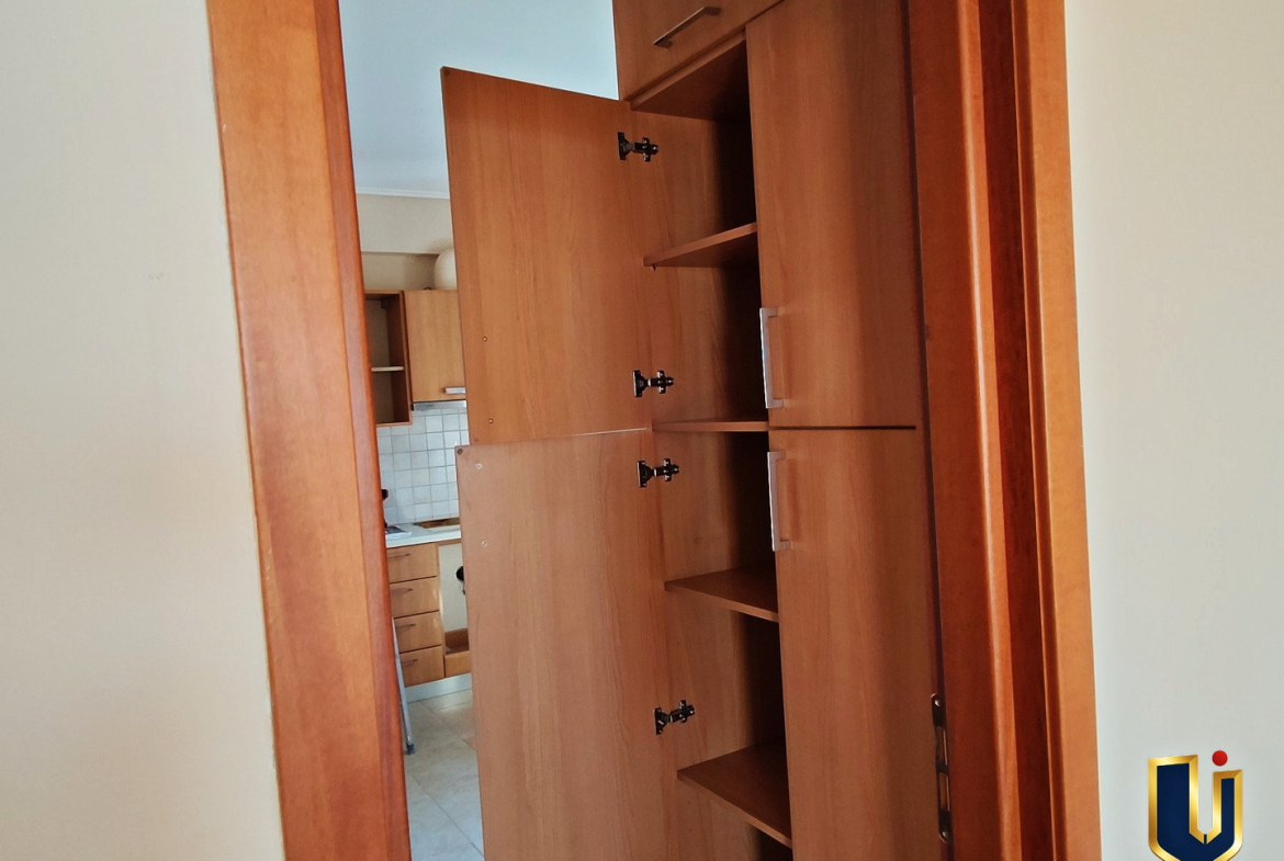 Tall wooden kitchen cupboard with open doors and internal shelves in a Paiania apartment