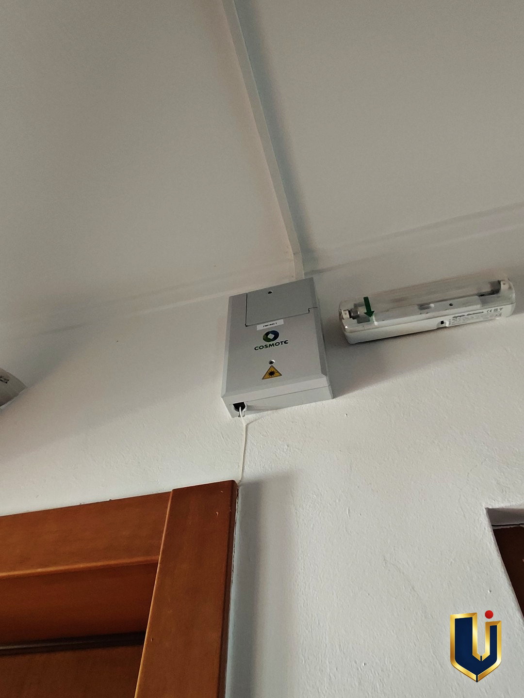 Fibre-optic connection box and cable conduit mounted above a doorway in a Paiania apartment