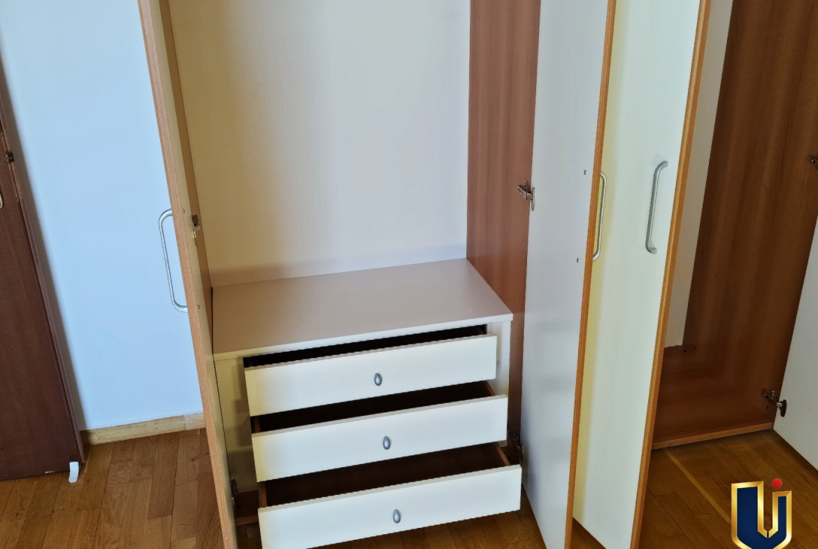 Open fitted wardrobe showing hanging space and three drawers in the second bedroom of a Paiania apartment