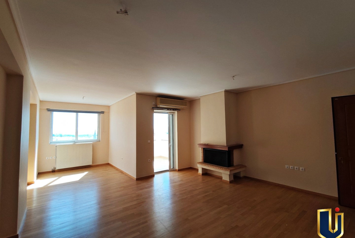 Living room with a fireplace, parquet flooring, a large window and balcony access in a Paiania apartment