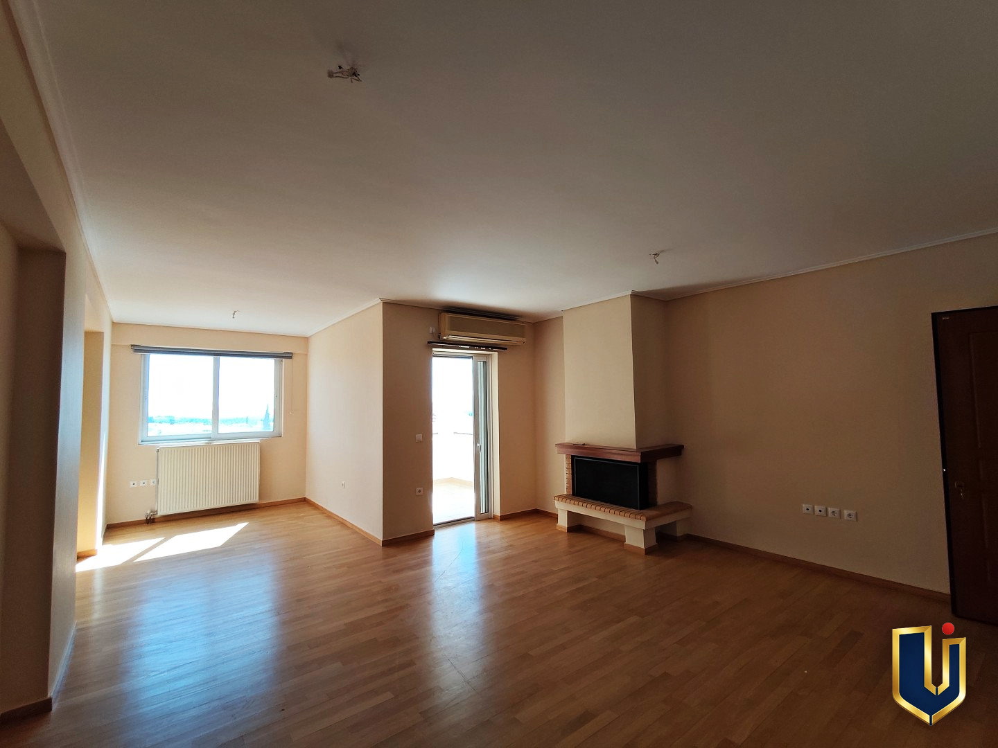 Living room with a fireplace, parquet flooring, a large window and balcony access in a Paiania apartment