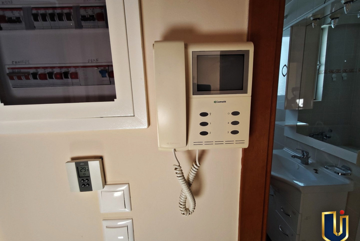 Video intercom, electrical panel and thermostat beside the bathroom doorway in a Paiania apartment