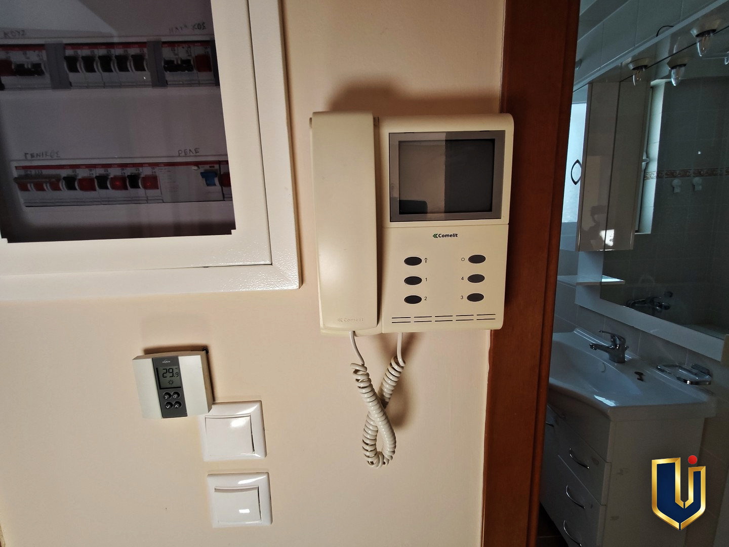 Video intercom, electrical panel and thermostat beside the bathroom doorway in a Paiania apartment