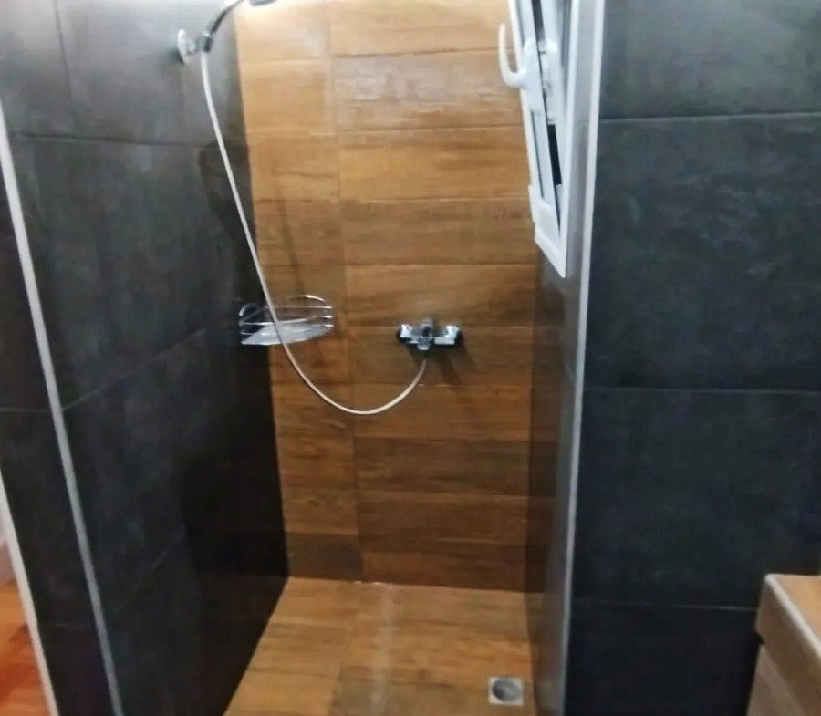 Glass-screen shower with wood-effect tiles in an apartment bathroom in Ano Patisia, Athens