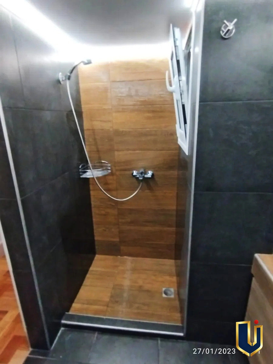 Glass-screen shower with wood-effect tiles in an apartment bathroom in Ano Patisia, Athens