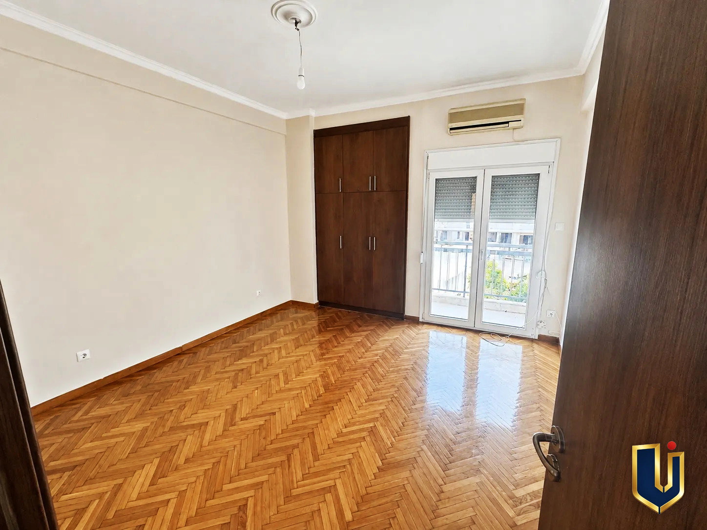 Second Bedroom in Kato Patissia Penthouse | Urban Keys Real Estate Second bedroom with wooden flooring and a balcony door in a renovated penthouse in Kato Patissia, Athens.