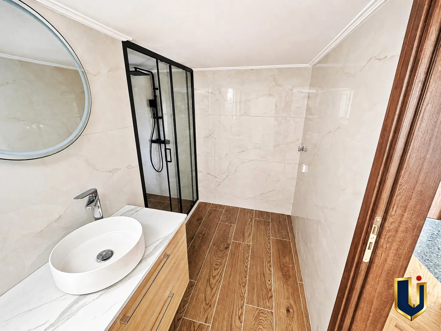 Bathroom with Shower in Kato Patissia Penthouse | Urban Keys Real Estate Compact bathroom with a toilet, glass shower enclosure, and light tiled walls in a renovated penthouse in Kato Patissia, Athens.