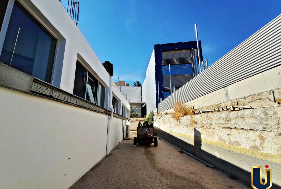 Paved side access passage beside a commercial property on Tatoiou Avenue in Metamorfosi, Attica.