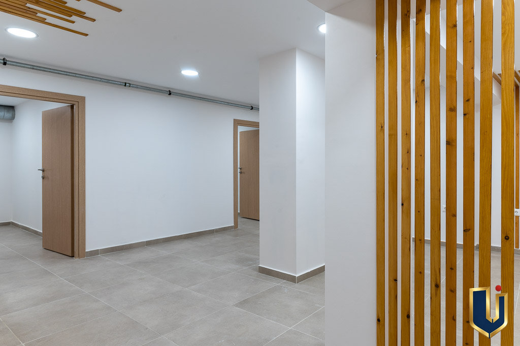 Bright interior hallway with tiled flooring, doorways, and vertical wooden slat details in the Athens investment building, property 150-1075.