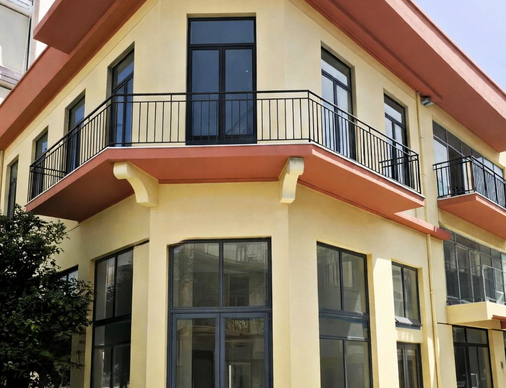 Corner building exterior with balconies and ground-floor commercial frontage in Piraeus.
