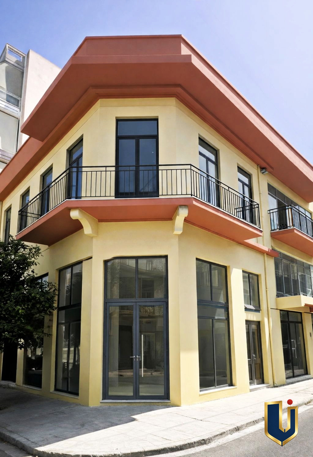 Corner building exterior with balconies and ground-floor commercial frontage in Piraeus.