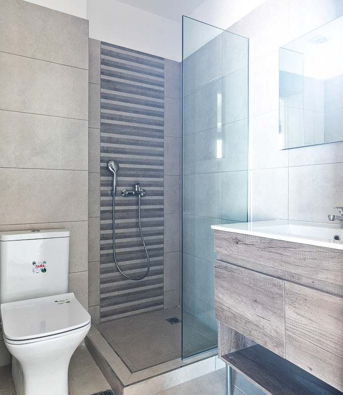 Bright apartment bathroom in Athens with a glass shower enclosure and toilet