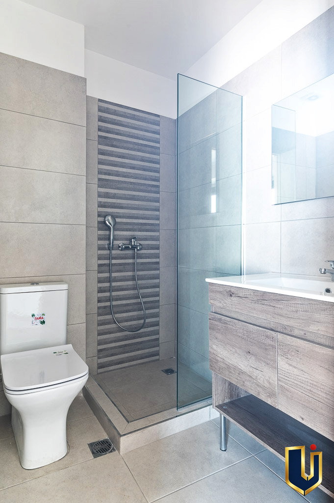 Bright apartment bathroom in Athens with a glass shower enclosure and toilet