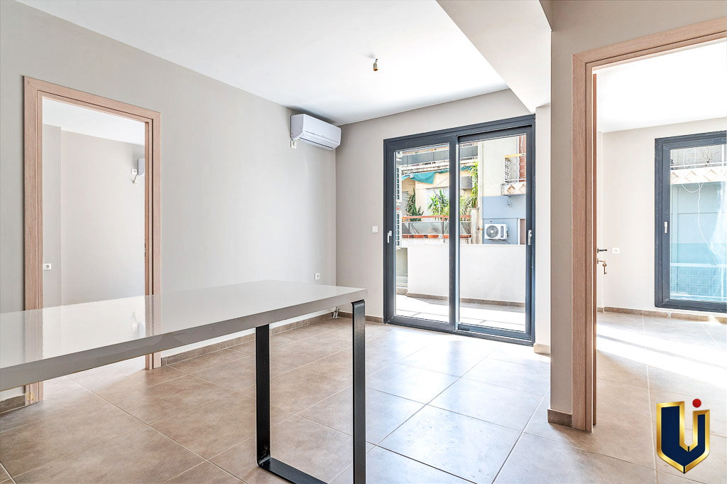 Bright apartment interior with wood flooring and large glass doors opening to a balcony.