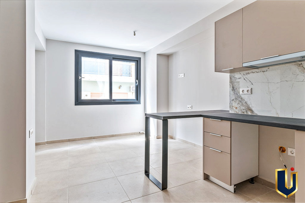 Apartment kitchen with light cabinetry, a counter, and a window, property 150-1075 in Athens.