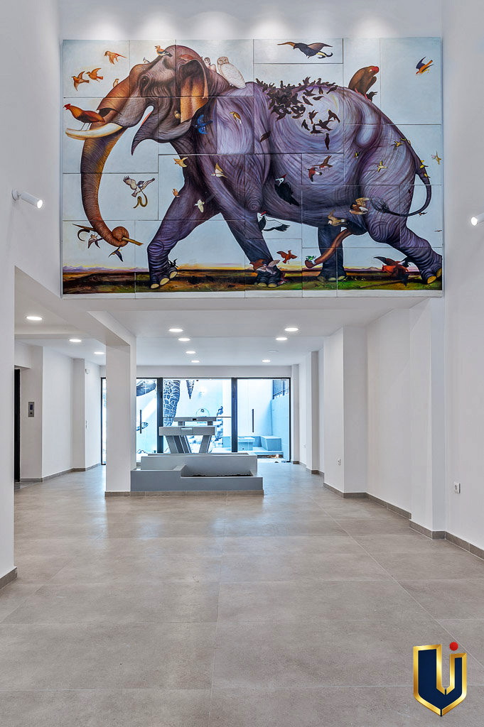 Interior lobby of an Athens building featuring a large elephant mural and a bright glass entrance