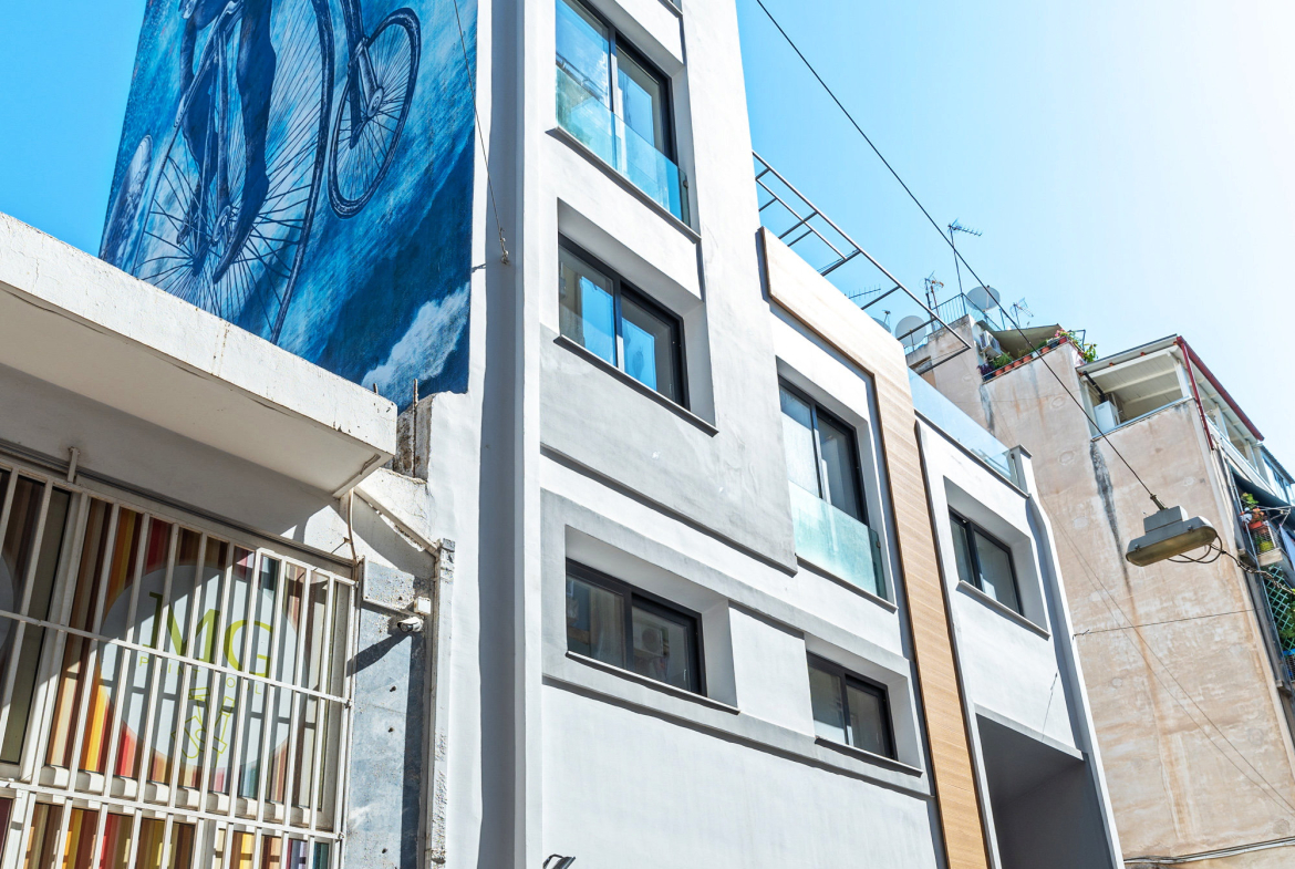 Modern white facade of an Athens investment building with balconies and a vertical wood-look panel, property 150-1075.