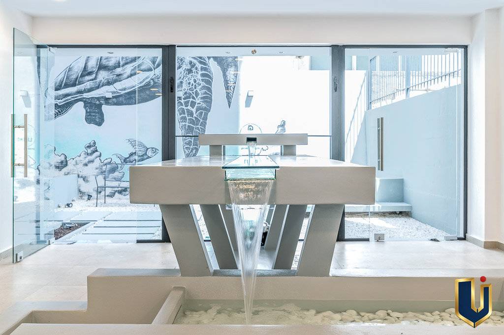 Shared indoor space with a table and chairs beside large windows overlooking the courtyard, property 150-1075 in Athens.