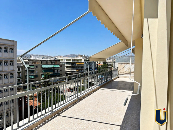 Large balcony with an awning and open city views at a renovated penthouse in Kato Patissia, Athens.