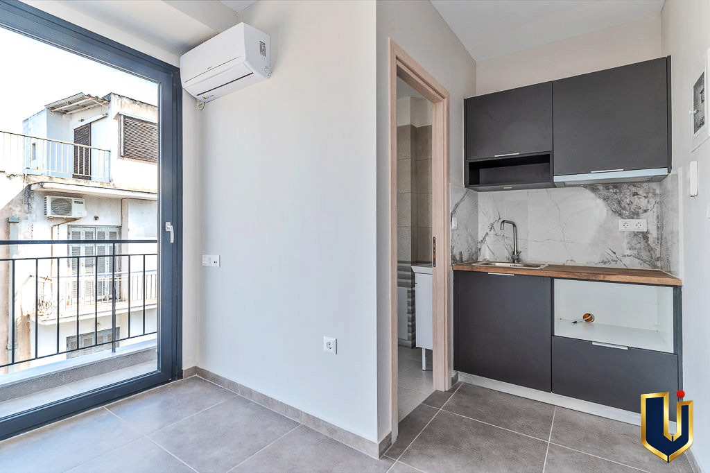 Apartment interior with balcony doors and a fitted kitchen beyond an interior opening, property 150-1075 in Athens.