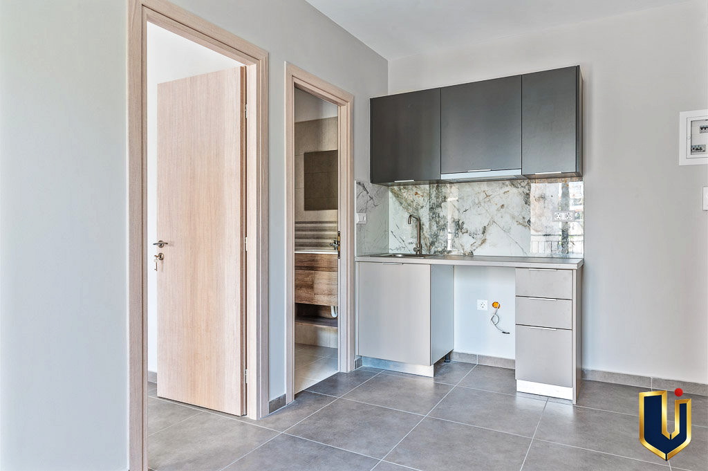 Apartment kitchenette and fitted cabinets viewed through an open doorway, property 150-1075 in Athens.