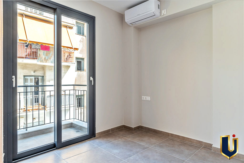 Bright apartment room with balcony doors, an air-conditioning unit, and wood flooring, property 150-1075 in Athens.